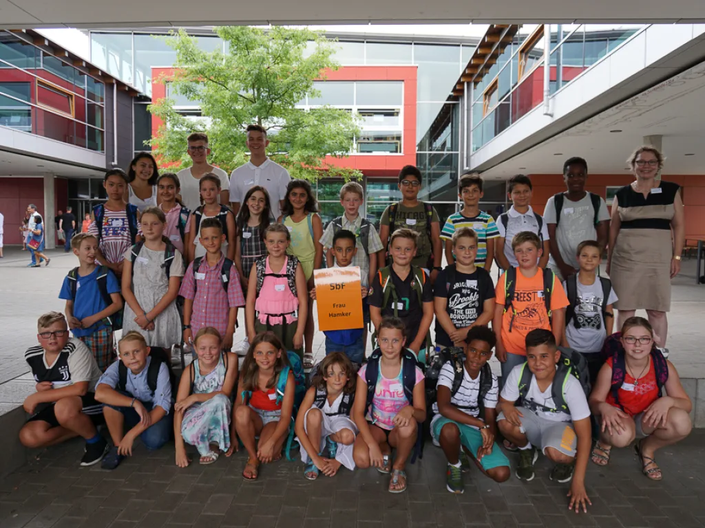 Klassenfoto einer neuen fünften Klasse mit orangem Schild.